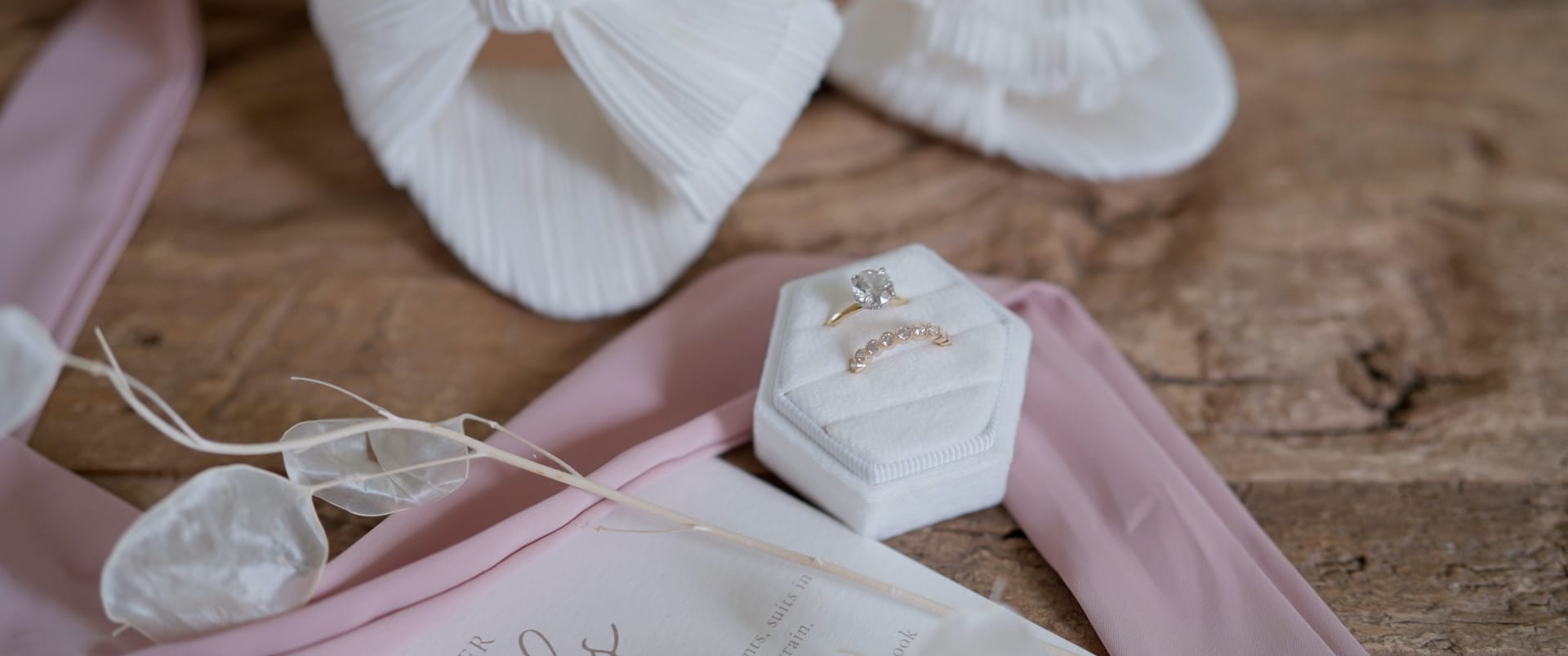 Wedding rings in a velvet box beside stationery and ribbon — documentary wedding film