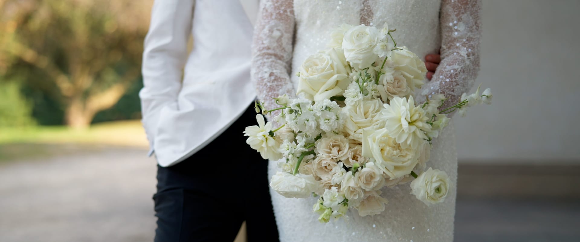 Bouquet of white roses held close against the wedding gown — documentary wedding film